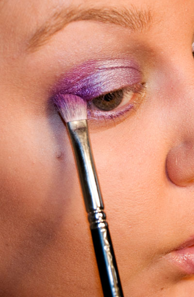 Applying medium violet powder eyeshadow